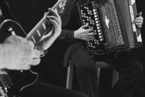 Close-up image of male hands playing guitar and accordion. Black and white photography. Retro culture